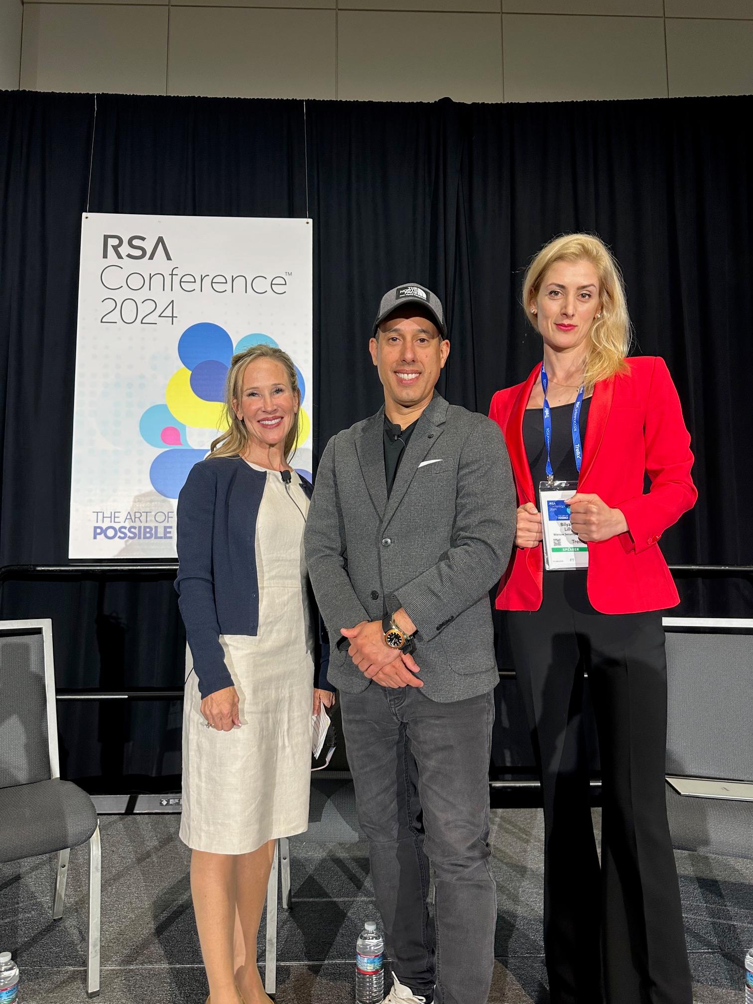 Panelists Sarah Cleveland, Lior Div, and Dr. Bilyana Lilly stand in front of an RSA Conference 2024 banner.