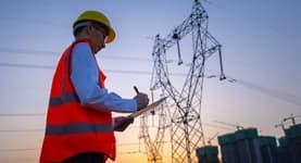 technician writing information down in front of the energy grid